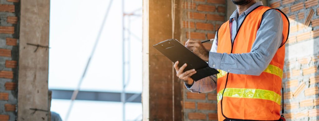 Inspector in a safety vest taking notes on a worksite